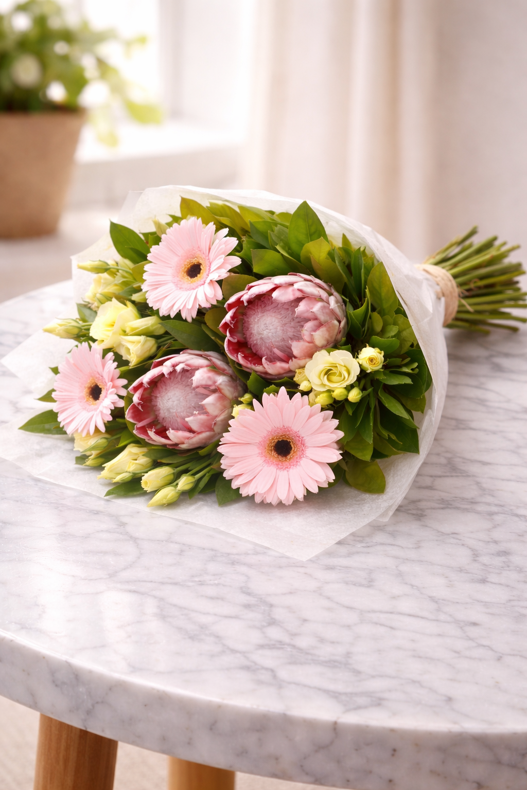 bouquet featuring gerberas, proteas and lisianthus, finished with fresh green foliage.