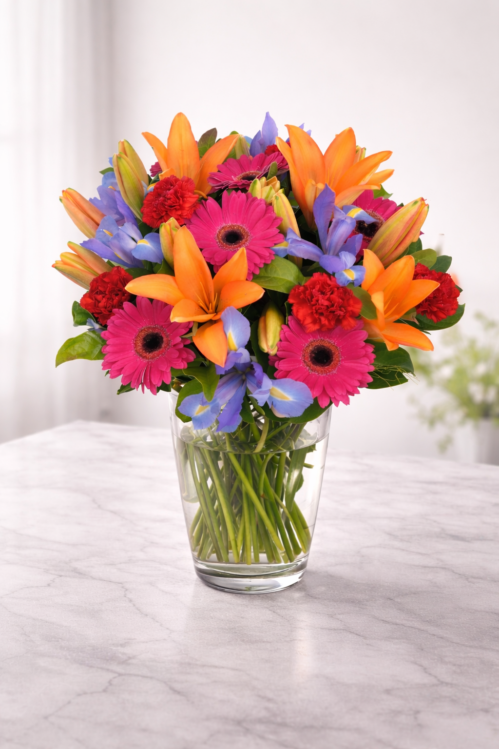 Bouquet of colourful flowers in a clear vase on a marble surface
