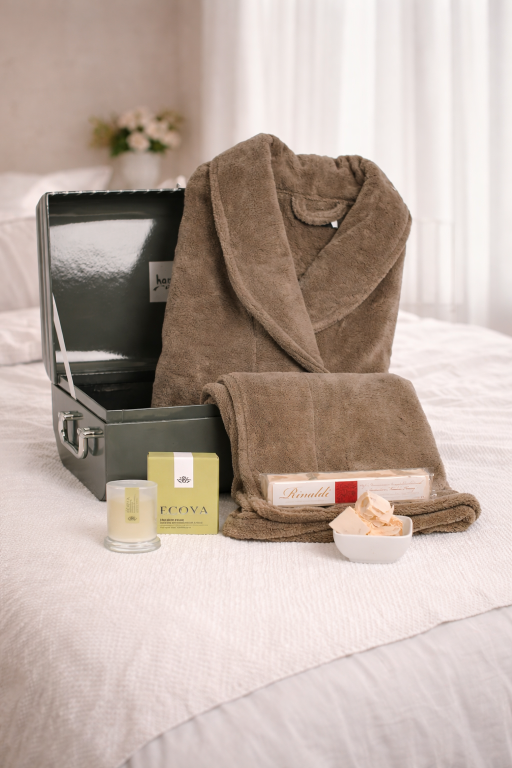 Brown robe, candle, and other items on a bed with a neutral background