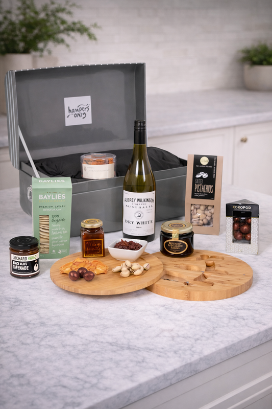 Wine and cheese platter with a bottle of wine, cheese, and other snacks on a kitchen counter.