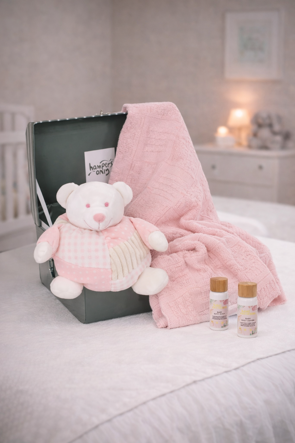 Pink teddy bear, blanket, and bottles on a bed in a bedroom setting